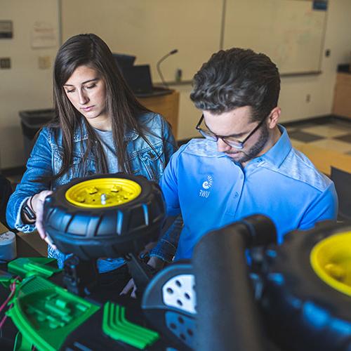 two engineering students working on an assistive vehicle